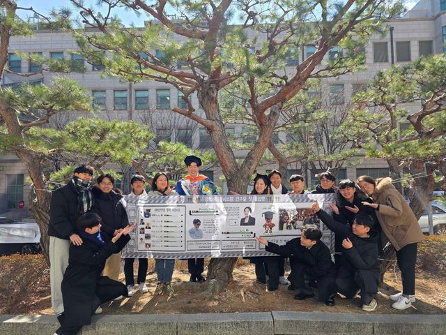 Kyung Chul's PhD graduation, with a banner for the lab's first graduate